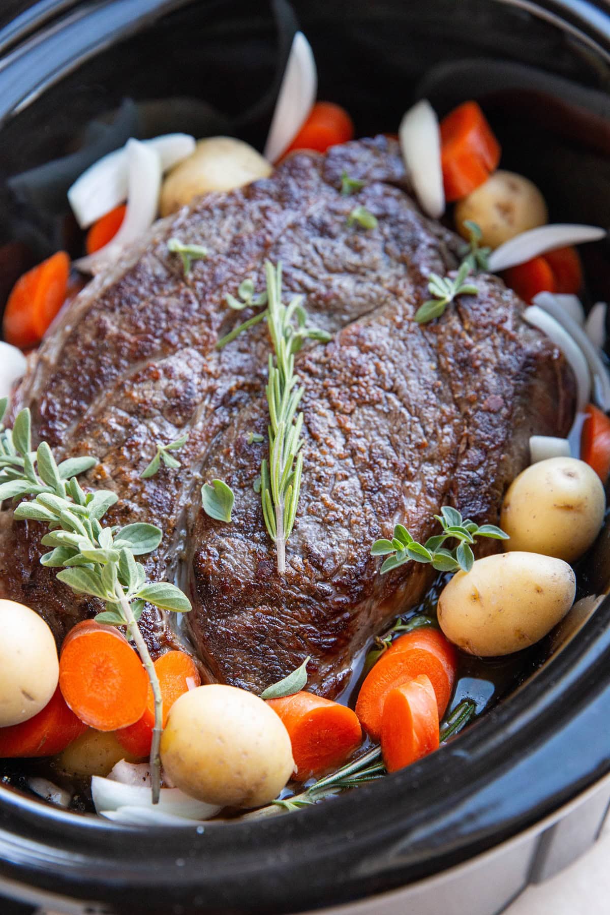 Crock pot with meat and vegetables inside, ready to slow cook.