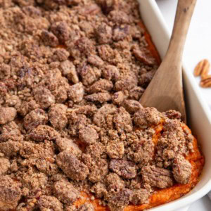 Large casserole dish of sweet potato casserole with pecan crumb topping.