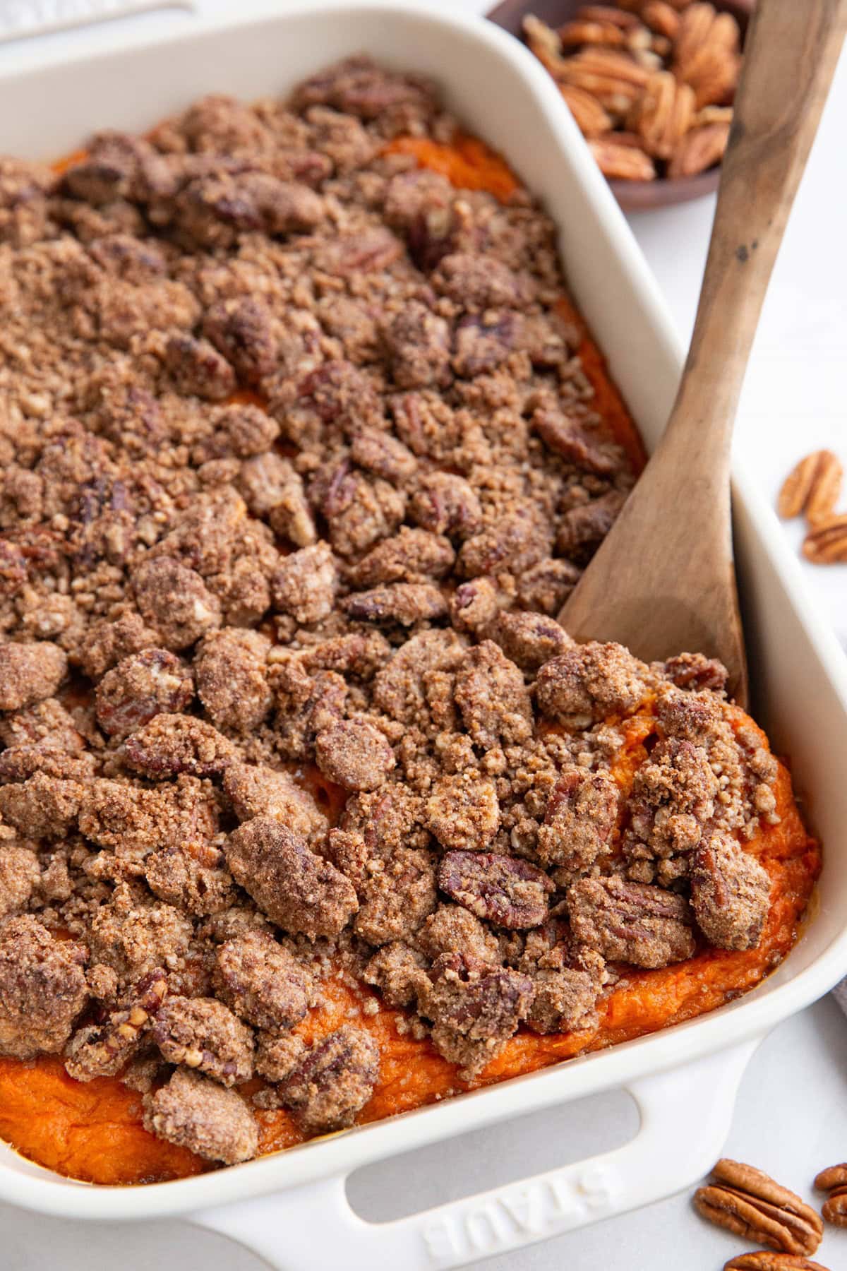 Large casserole dish of sweet potato casserole with pecan crumb topping.