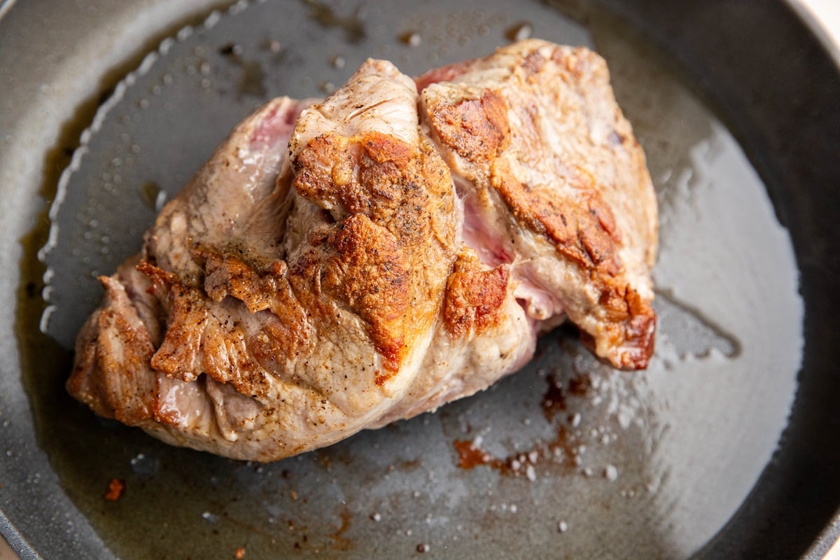 Pork roast searing in a skillet.