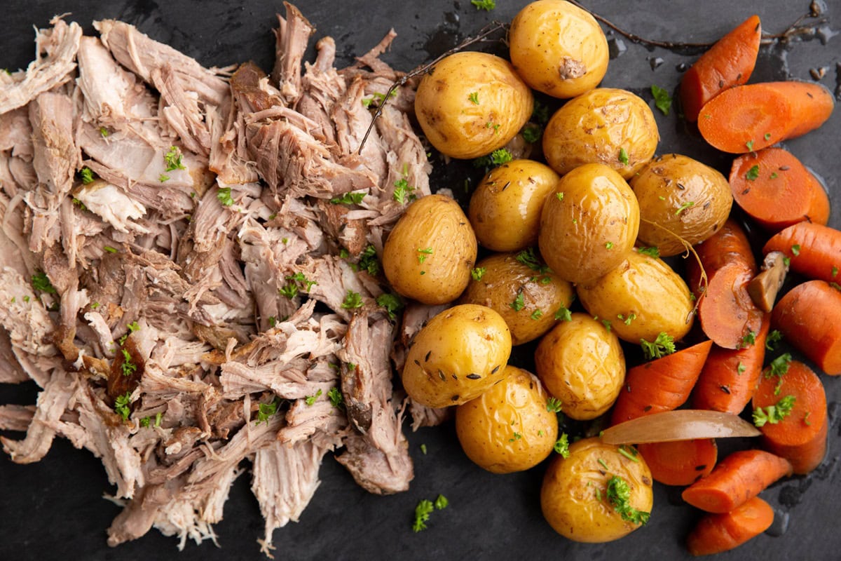 Black slate with shredded pork, potatoes, and carrots on top, ready to serve.