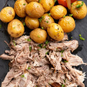 Shredded pork, potatoes, and carrots on a black serving platter.