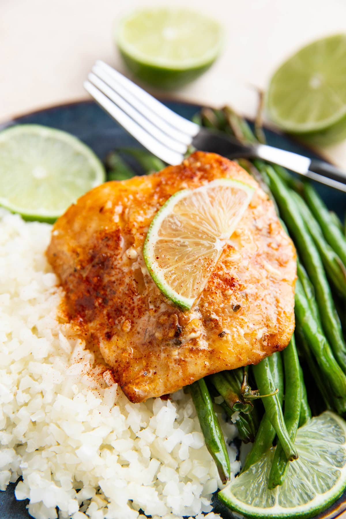 Chili lime cod on a plate with cauliflower rice and green beans.