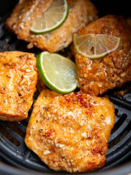 Four cod filets in an air fryer freshly air fried and ready to eat.
