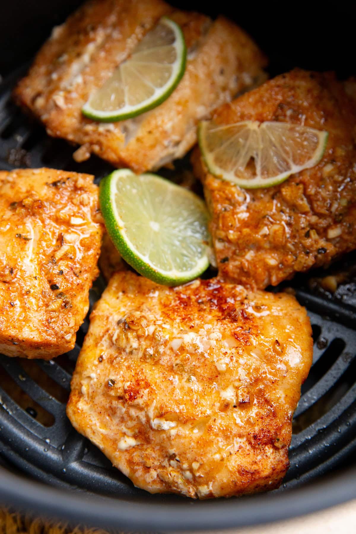 Four cod filets in an air fryer freshly air fried and ready to eat.