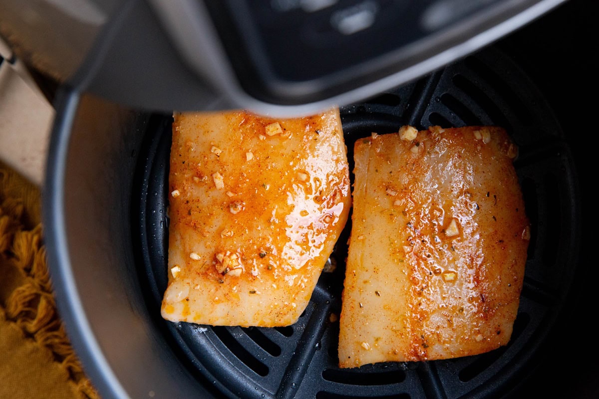 Marinated cod in an air fryer, ready to air fry.