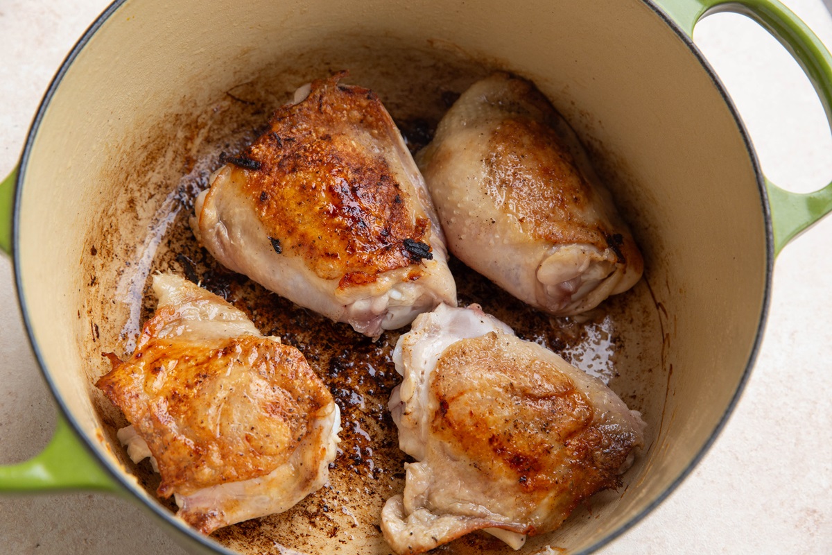 Browned chicken in a Dutch oven for caramelized onion chicken.