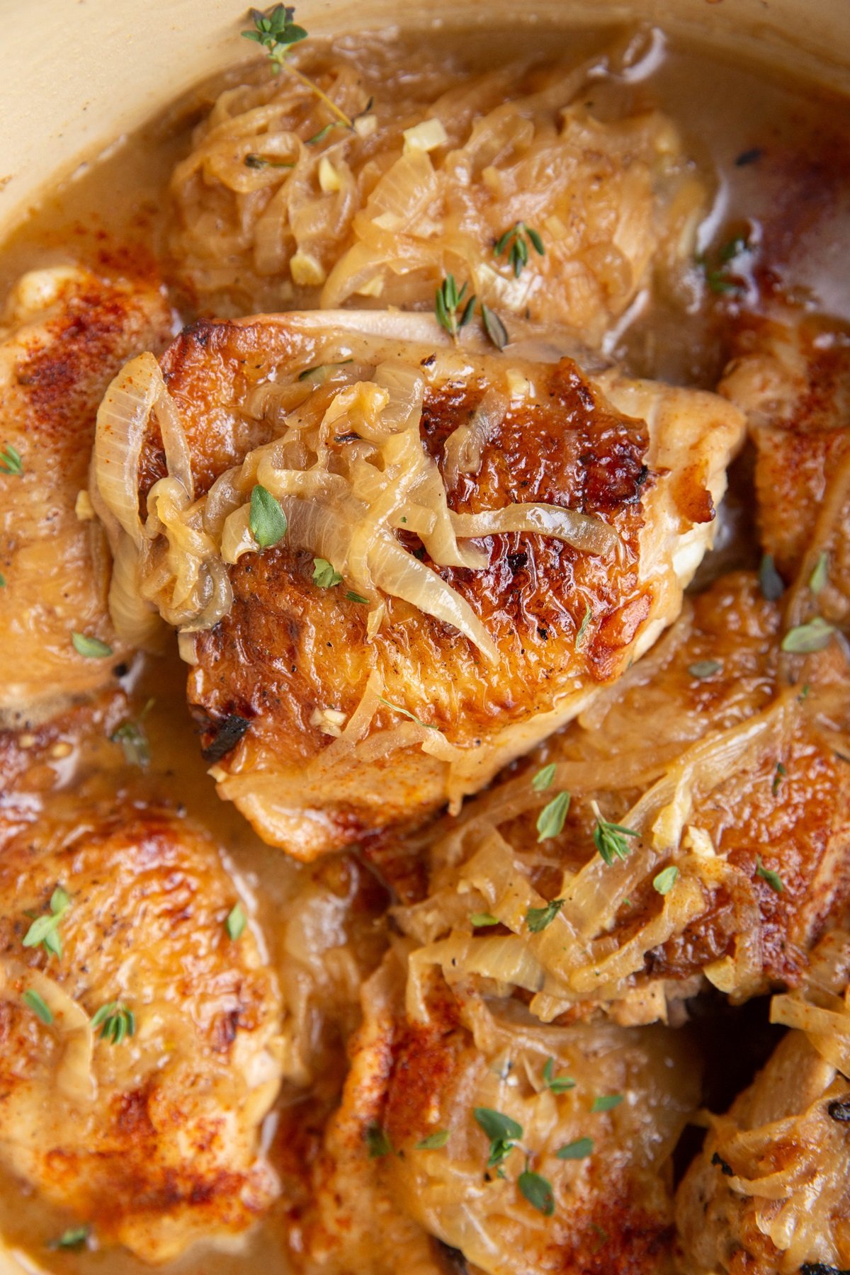Close up chicken thighs with caramelized onions on top.