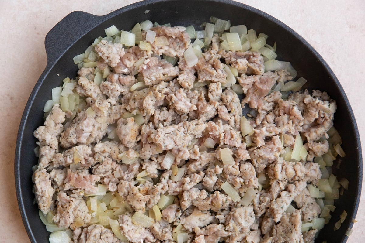 Sausage and onion cooking in a skillet.