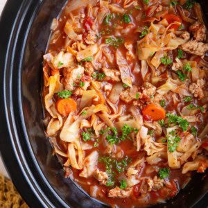 Slow Cooker full of sausage and cabbage soup. Garnished with parsley and ready to serve.