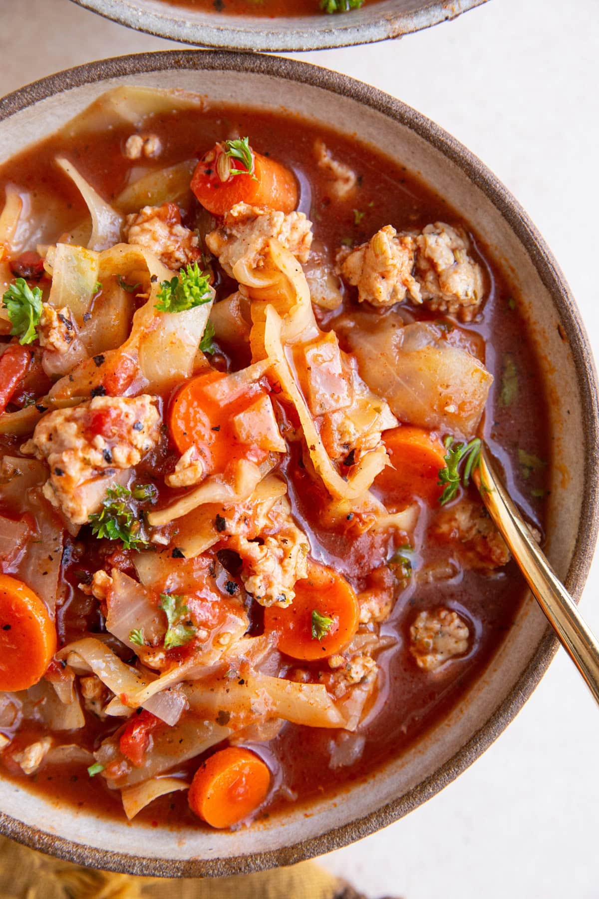 Big bowl of sausage and cabbage soup with fresh vegetables and tomato broth.