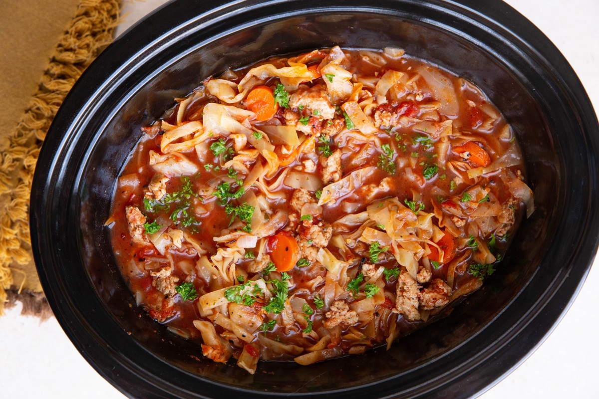Slow cooker full of sausage and cabbage soup.