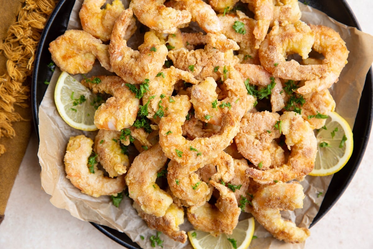 Plate of breaded shrimp with lemon wedges and a napkin to the side, ready to serve.