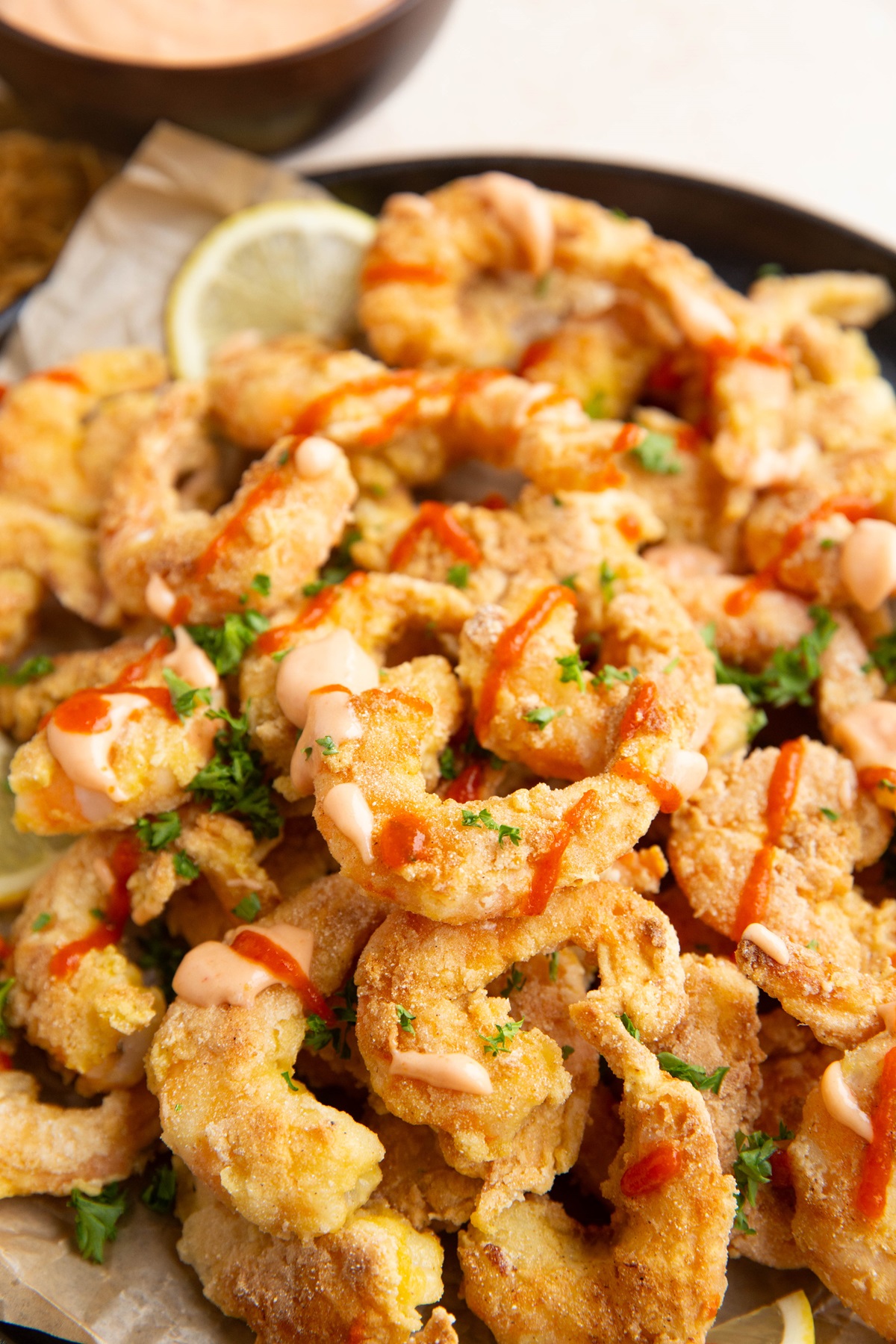 Crispy shrimp on a plate drizzled with sauce and fresh parsley, ready to serve.