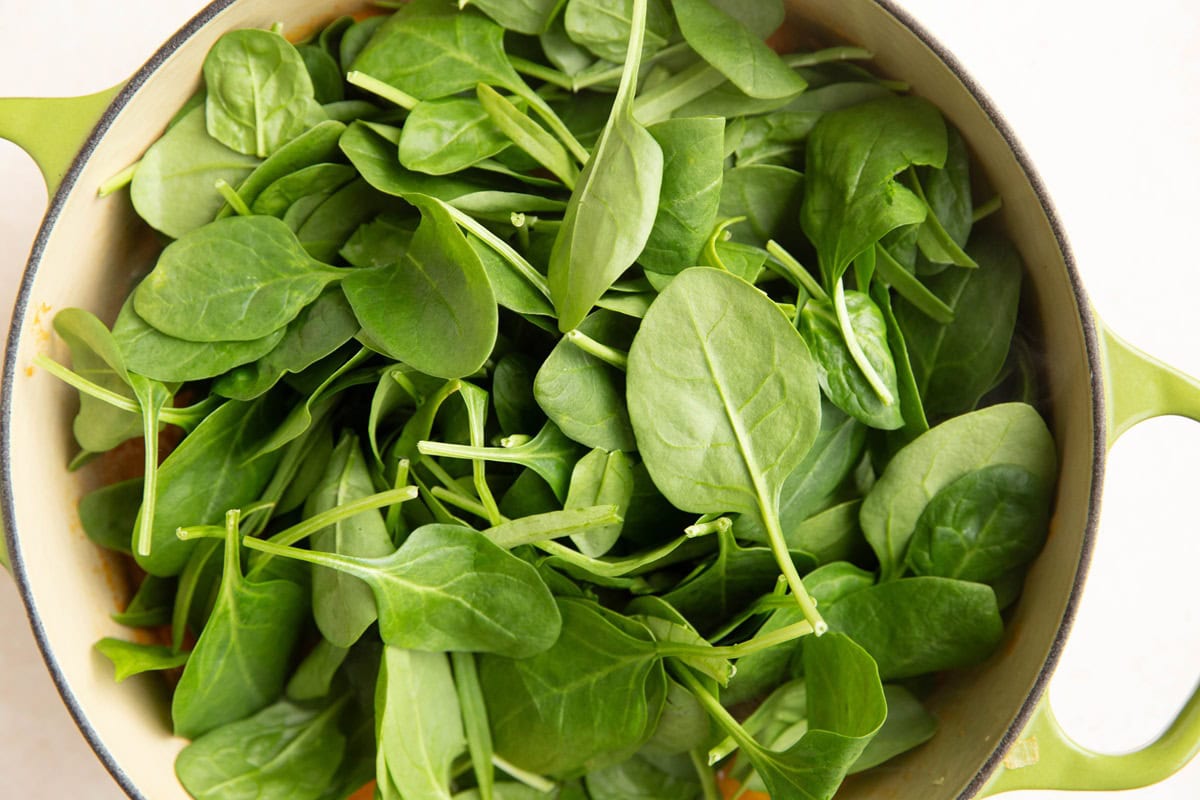 Baby spinach on top of curry soup, ready to be mixed in.