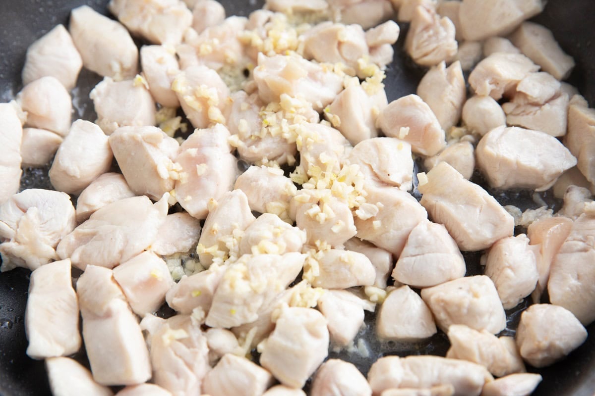 Chicken browning in a skillet with garlic.