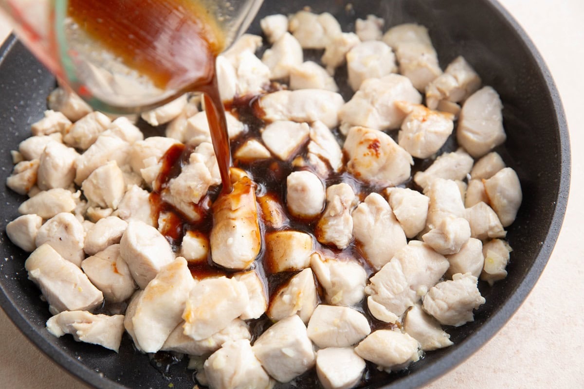 Pouring the sauce into the skillet with the chicken