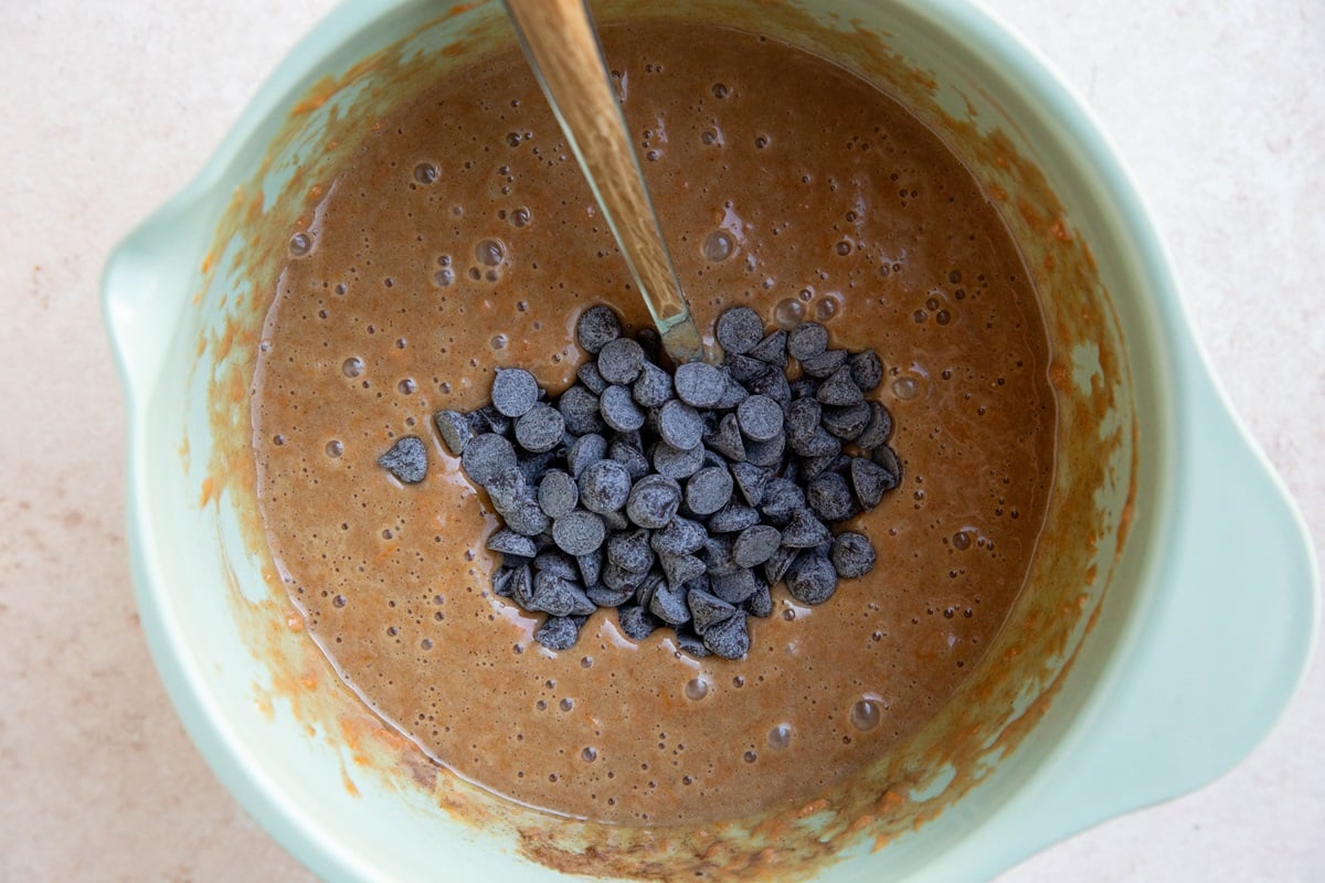 Sweet potato muffin batter in a mixing bowl with chocolate chips on top.