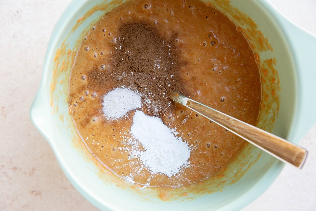 Sweet potato muffin batter in a mixing bowl with dry ingredients added in.