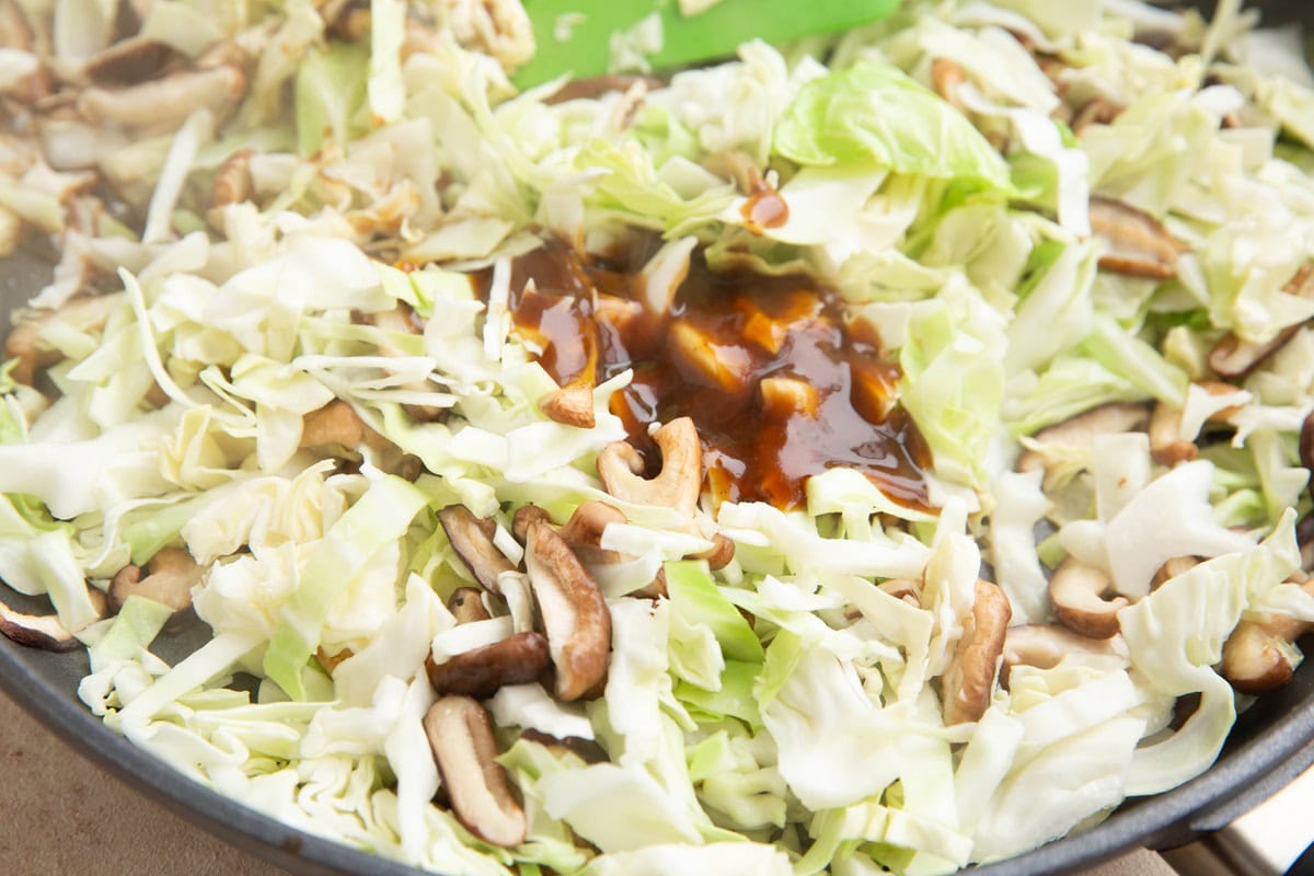 Mushrooms, cabbage and sauce in a skillet.