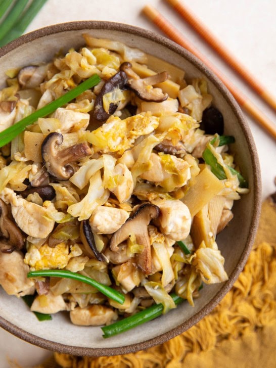 Bowl of moo shu chicken with chop sticks to the side and a napkin next to the bowl..