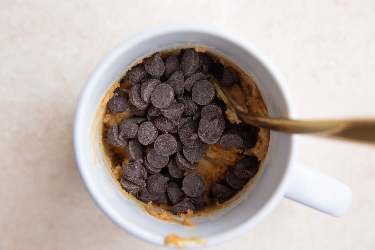 Mug with cake batter and chocolate chips sprinkled on top.