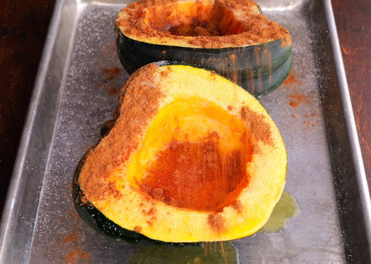 Acorn squash being sprinkled with ground cinnamon.