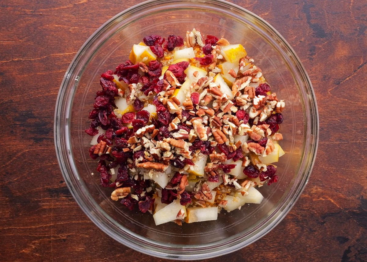 Chopped pears, pecans, dried cranberries and quinoa in a bowl, ready to be mixed up.