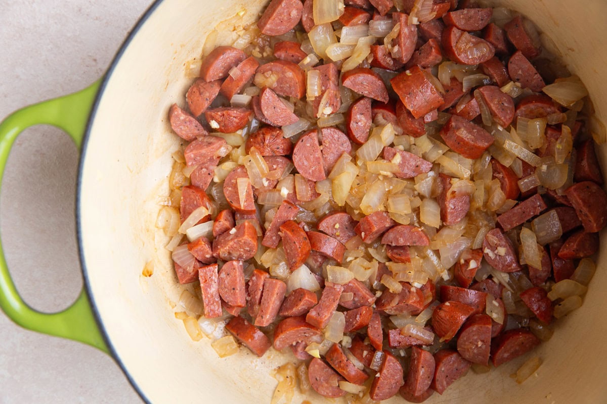 Onion and sausage cooking in a large pot.