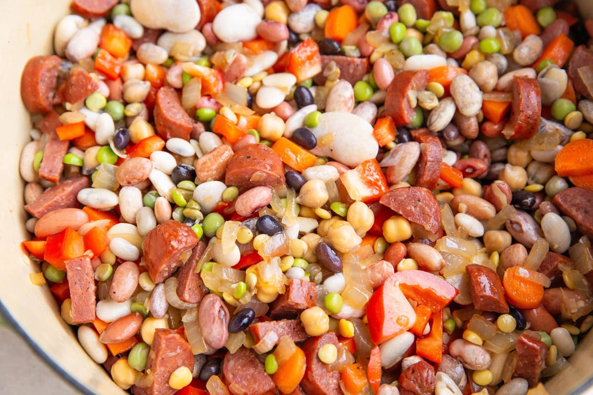 Large pot of beans, sausage and onions, being turned into soup.