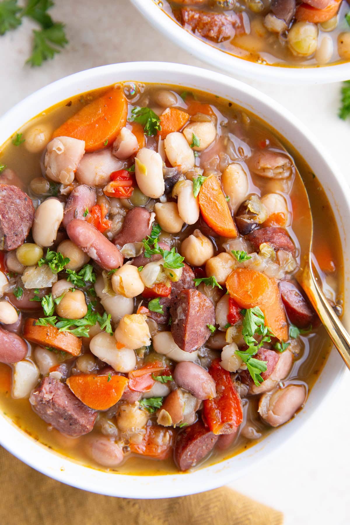 Teo bowls of sausage and bean soup. Closeup so you can see all the different types of beans.