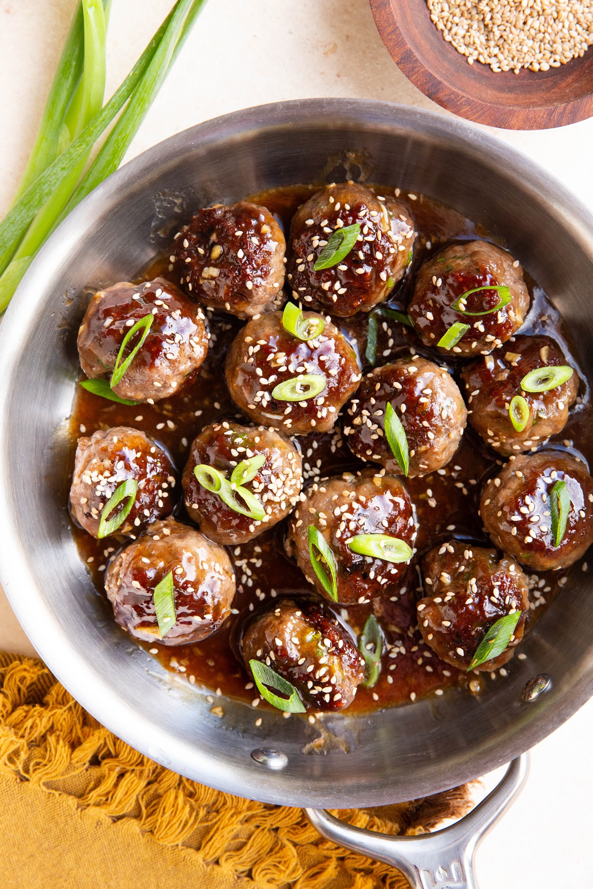 stainless steel skillet with sesame garlic meatballs inside, ready to serve.