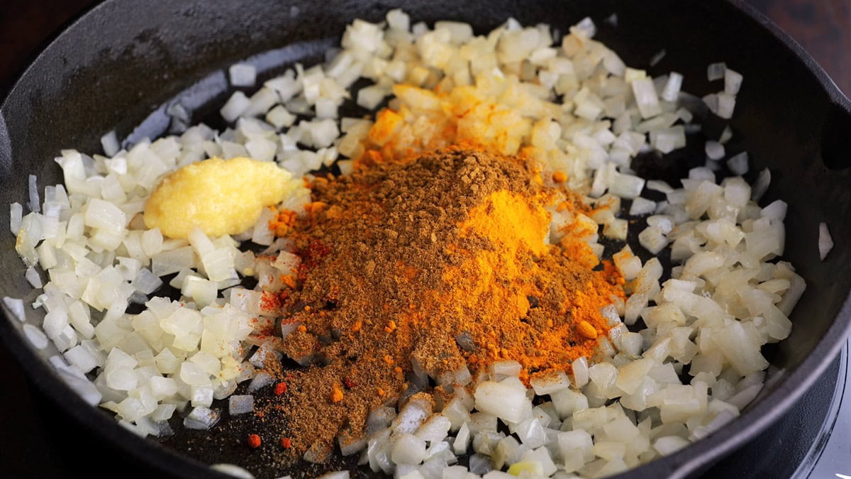 Cast iron skillet of chopped onions and seasonings.