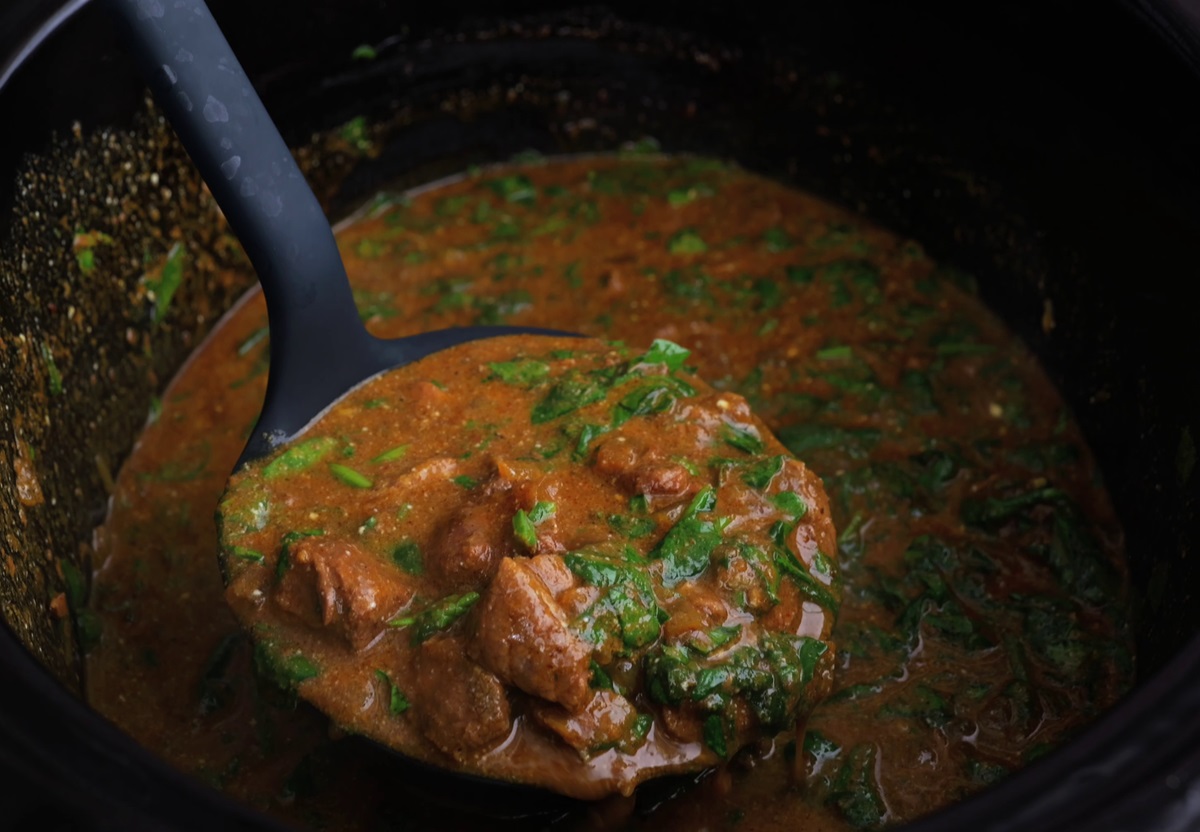 Ladle holding a portion of crock pot lamb curry.