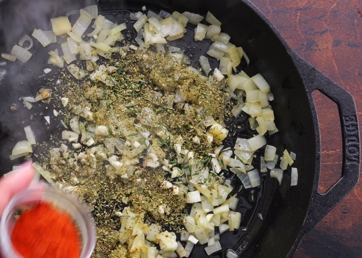 Onion sautéing in a skillet with dried herbs and seasonings.
