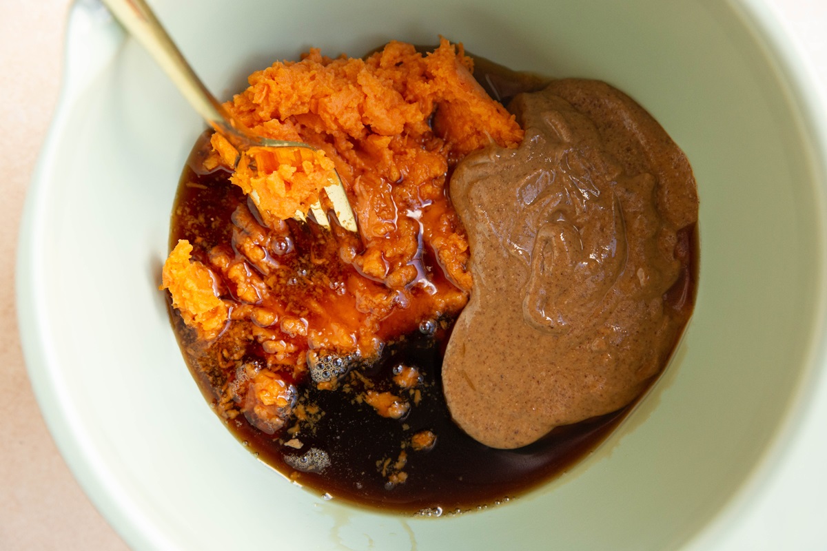 Mashed sweet potato, almond butter, and pure maple syrup in a mixing bowl.