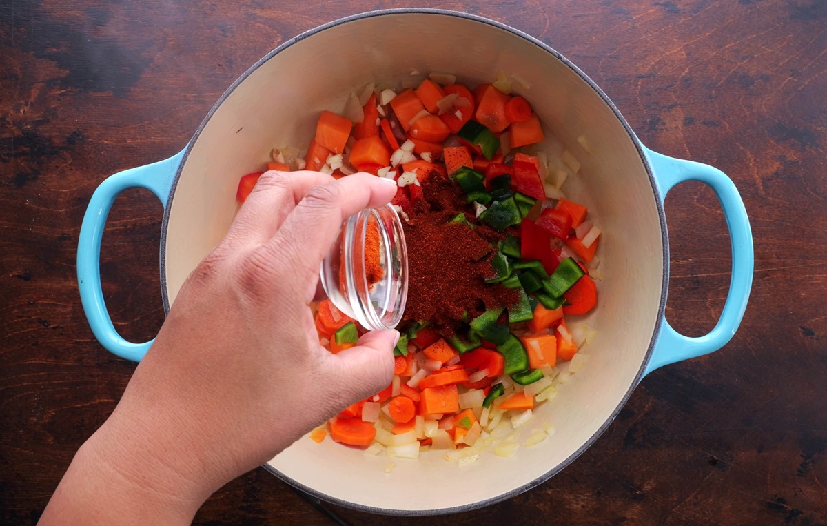 Sprinkling seasonings over fresh vegetables for chili.