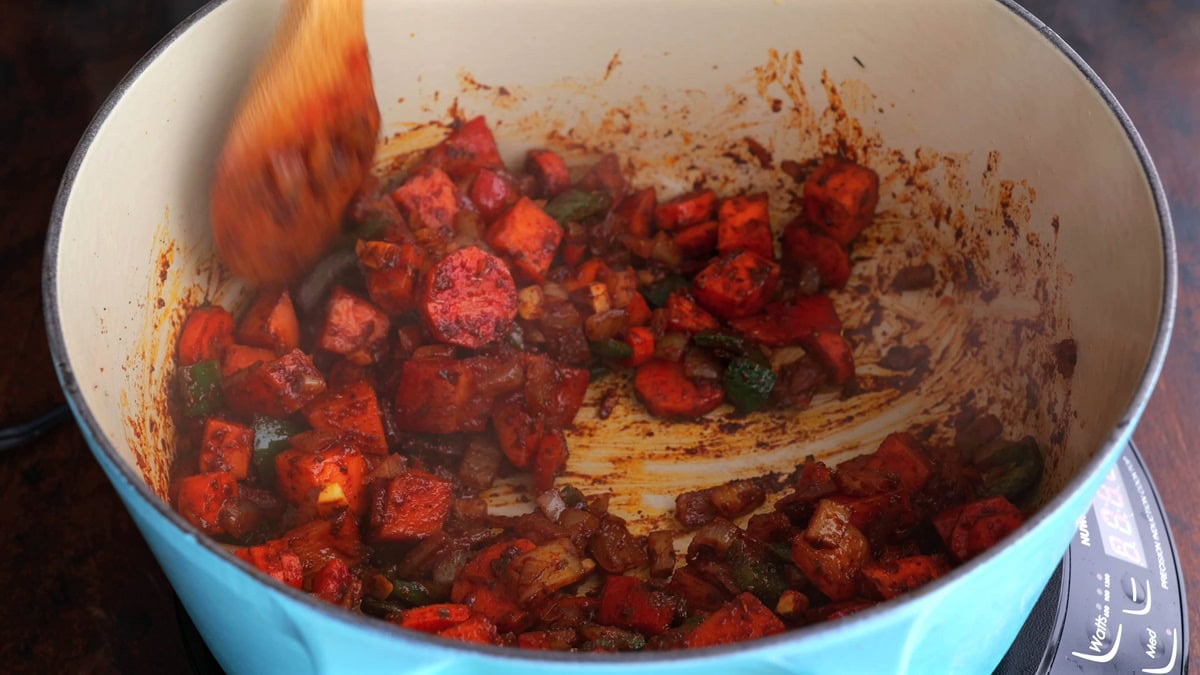 Stirring vegetables and seasonings in a large pot.