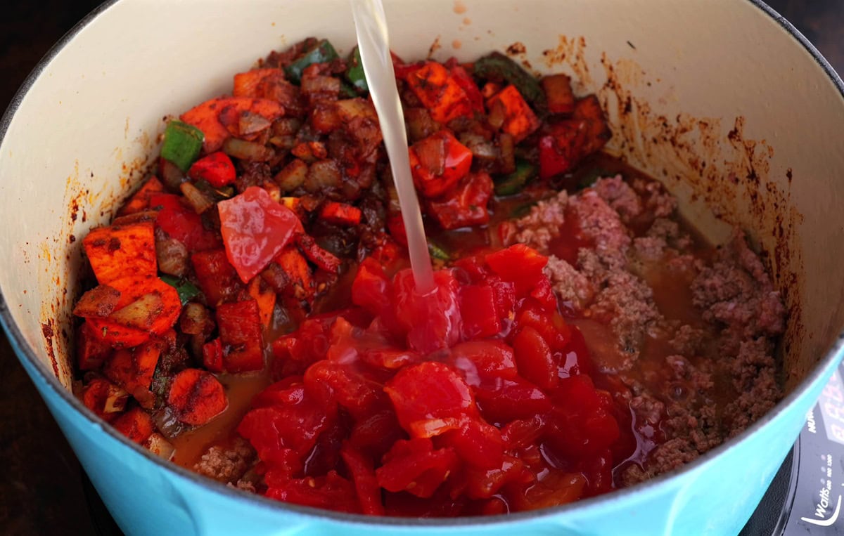 Pouring broth into the pot with the remaining ingredients.