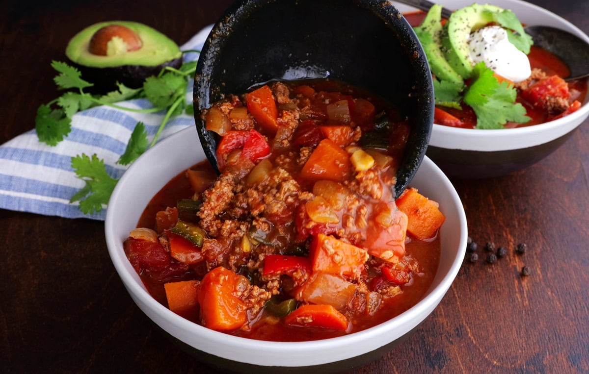 Ladling a scoop of chili into a bowl.