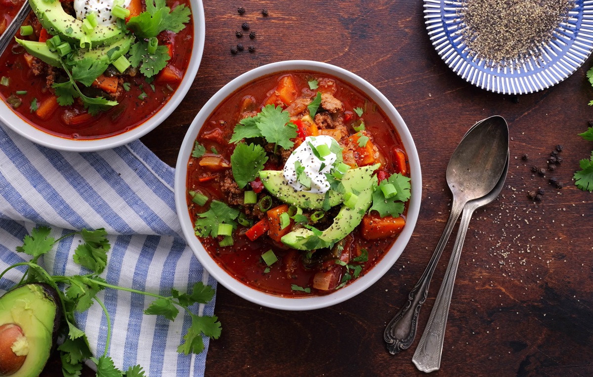 Two bowls of turkey chili with pepper and sliced avocado.