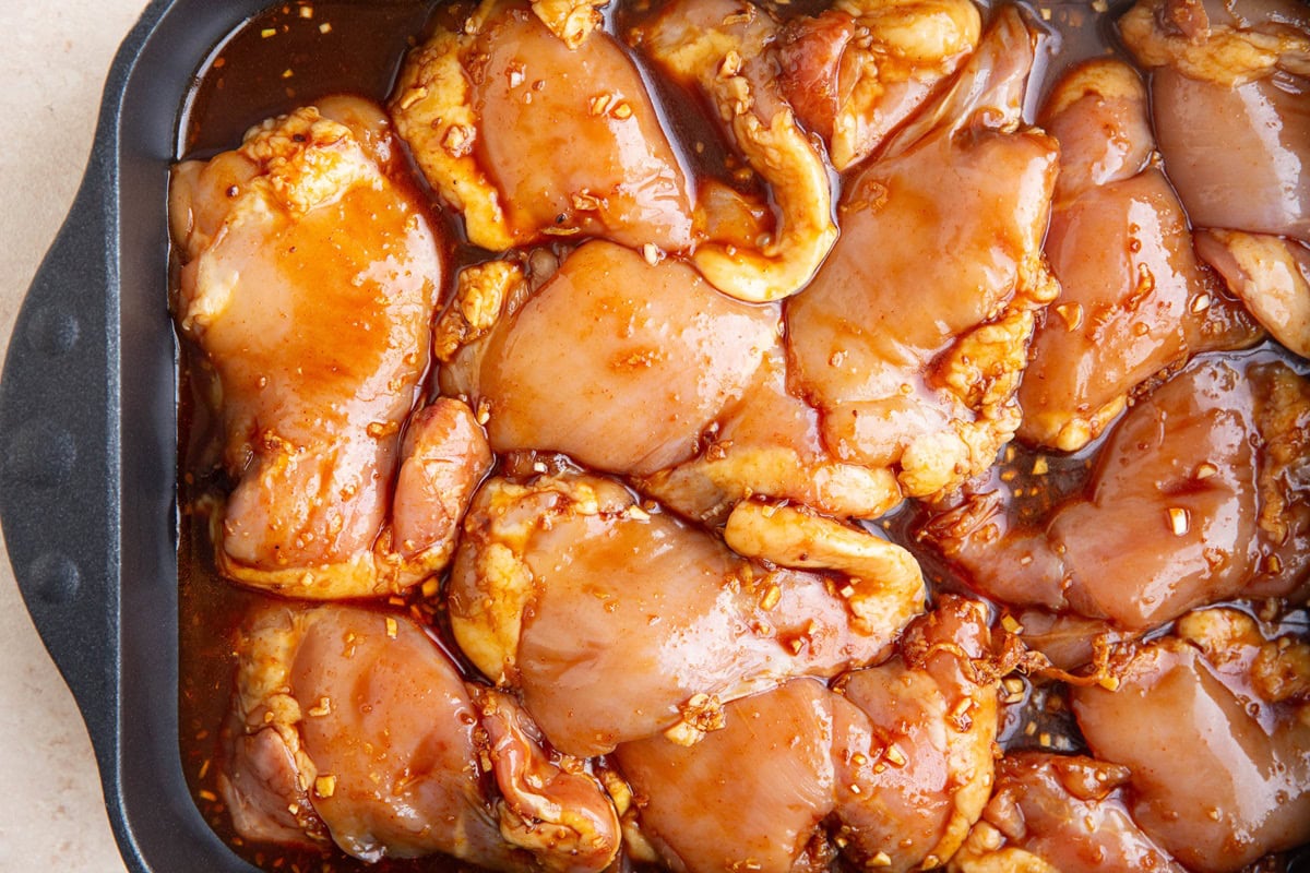 Large baking dish full of raw marinated chicken, ready to go into the oven.