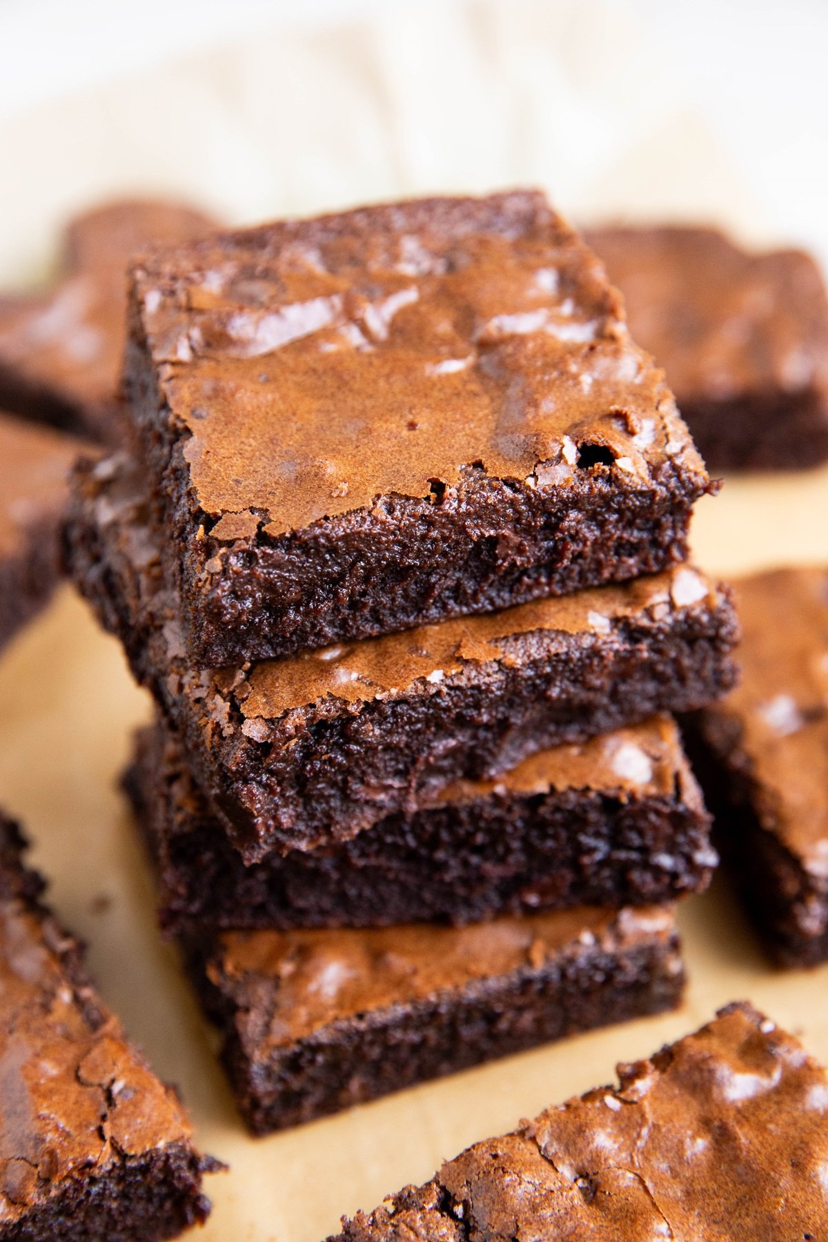 Stack of chewy brownies on a sheet of parchment paper, ready to serve.
