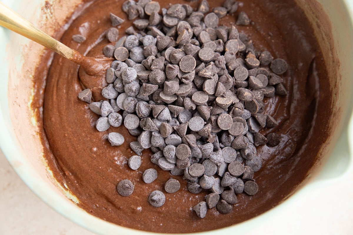 Chocolate chips on top of brownie batter in a mixing bowl.