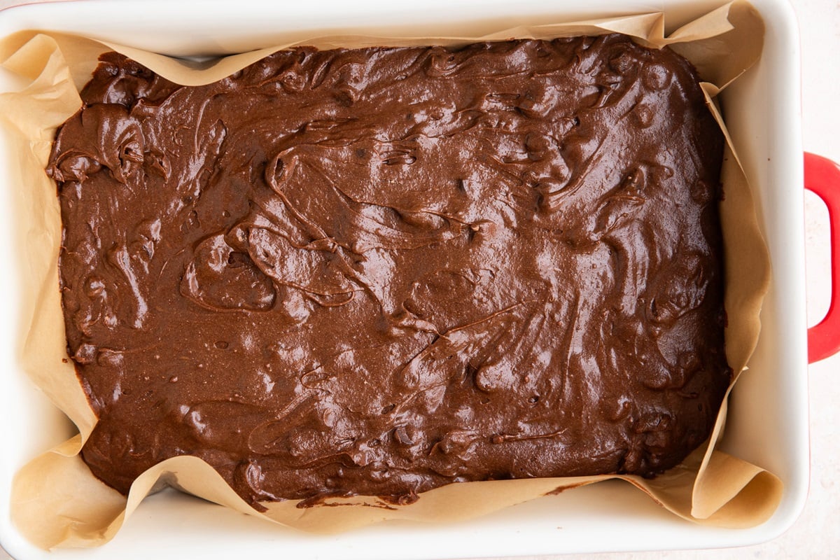 Brownie batter in a parchment lined baking pan.