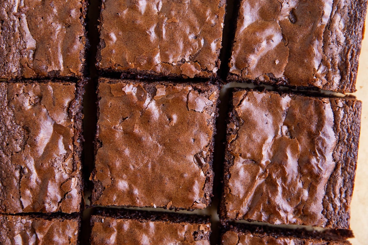 Brownies cut into individual slices on a sheet of parchment paper.