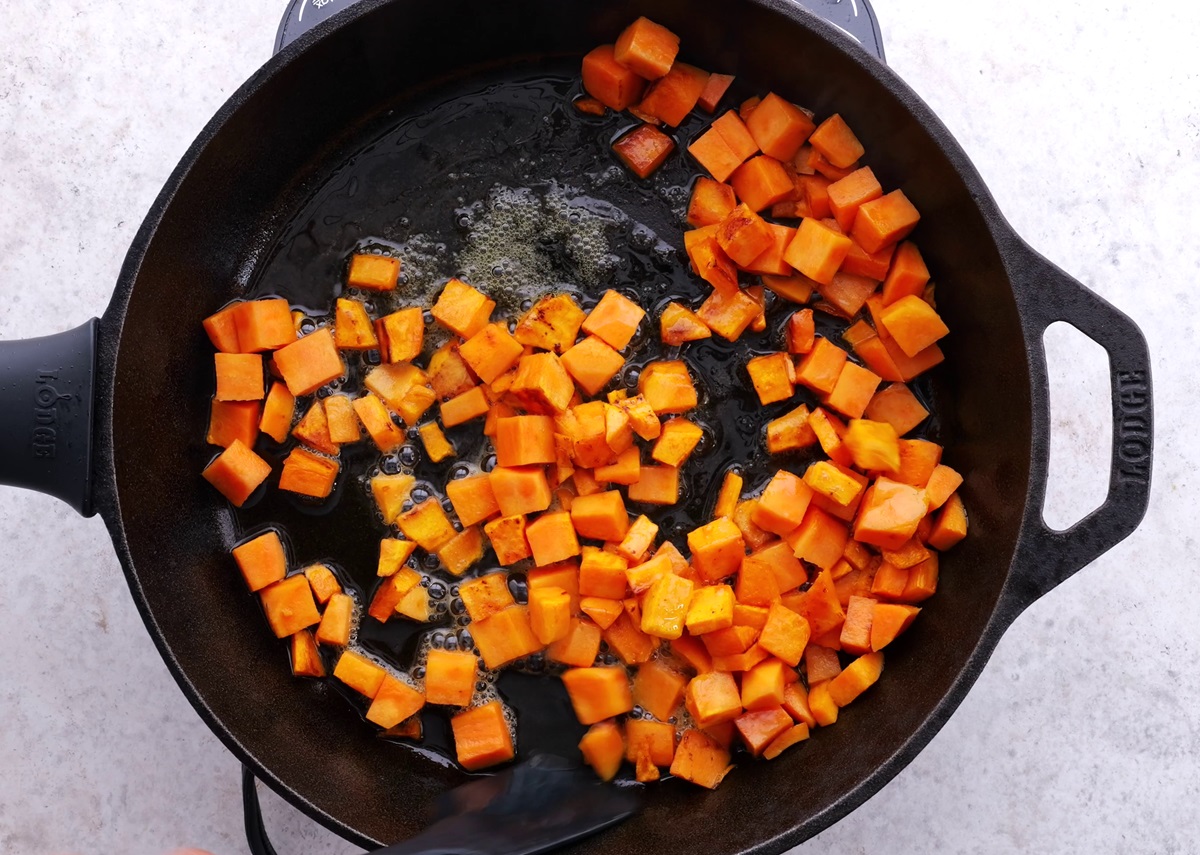 Sweet potatoes cooking in a cast iron skillet.