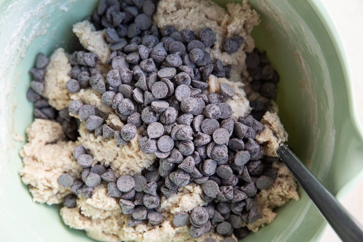 Chocolate chips on top of scone dough in a mixing bowl.