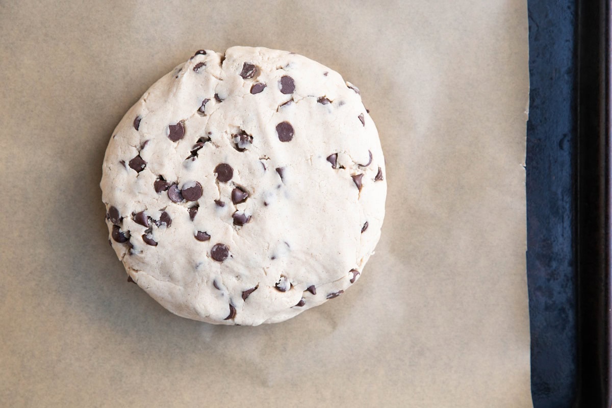 Disc of scone dough on a parchment lined baking sheet.