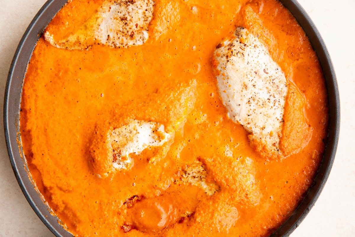 Chicken and roasted red pepper sauce in a large skillet.